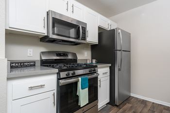 A kitchen with a black refrigerator, stove, and microwave.